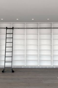 an empty room with shelves and ladders in the middle, there is no one on the floor