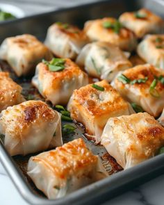 some dumplings are sitting in a pan on a table with green garnish