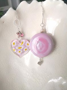 These lovely mismatched earrings are a beautiful shade of opaque pink Venetian Murano glass. The thick blown glass penny bead ( a round bead which has been partially flattened) measures approx 38mm (3.8cm or approx 1.5) and 16mm (1.6cm or 5/8")  It hangs from a Sterling silver oval hoop which in turns hangs from a Sterling silver fish hook earwire and below dangles a small Sterling silver heart. The millefiori glass heart bead measures 34mm (3.4cm or not far off 1.5") It features millefiori to t Pink Glass Round Jewelry, Pink Round Glass Jewelry, Handmade Pink Glass Jewelry, Unique Pink Round Bead Earrings, Heart-shaped Pink Glass Jewelry, Pink Heart-shaped Glass Jewelry, Pink Sterling Silver Round Bead Earrings, Silver Fish, Mismatched Earrings