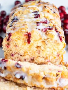 cranberry orange scones with icing on a white plate next to fresh cranberries