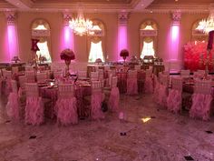 an elegant ballroom with pink lighting and chandeliers on the ceiling, decorated for a wedding