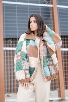 a woman is wearing a multicolored sweater and pants while standing in front of a building