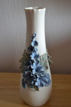 a white vase with blue flowers on it