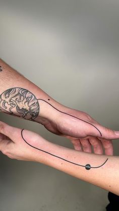 two hands holding each other with tattoos on their arm and wrist, one has a brain in the middle