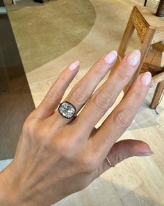 a woman's hand with a ring on it and a chair in the background