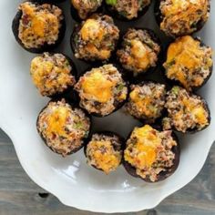 a white plate topped with stuffed mushrooms covered in cheese and seasoning sitting on top of a wooden table