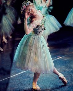 a young ballerina is talking on her cell phone in front of other ballet dancers