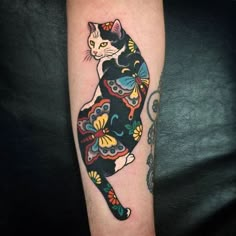 a black and white cat tattoo on the right arm, with colorful flowers around it