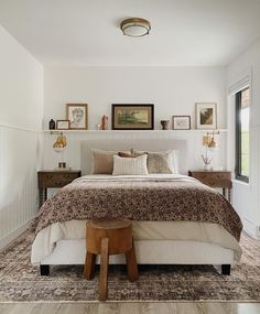 a bedroom with white walls and wood flooring has a large bed in the center