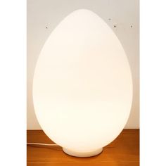 an egg shaped lamp sitting on top of a wooden table