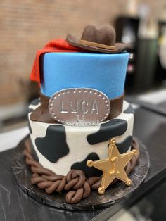 a three tiered cake decorated with cowboy hats and rope