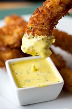 a plate with some fried food on it and dipping sauce in the bowl next to it