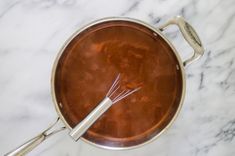 a saucepan with whisk in it on a marble counter top