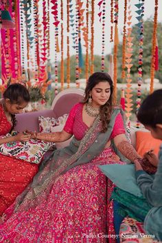 two women sitting on a couch in front of a man and another woman wearing colorful clothing