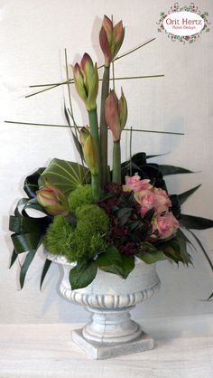 a white vase filled with flowers and greenery