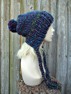 "Style: Slightly slouchy, split brim hat with long braided ties and a large pom pom on top. Color: This sample hat is shown in City Lights, subtle stripes of grass green, mustard, royal blue, fuchsia, aqua and tomato red against a navy blue base. Sizes: One size fits average teen or adult head size of 20\" to 23\" (50.5 cm to 58 cm). Fiber Content: 80% acrylic, 20% Wool Characteristics: Chunky, very soft, warm and cozy. Care Instructions: Hand wash, dry flat. Every item from Pixiebell is handmad Slouchy Hat Crochet Pattern, Charlotte City, Crochet Newsboy Hat, Hat Pom Pom, Yarn Ideas, Flap Hat, Chunky Knit Hat, Ear Flap Hats, Pixie Hat