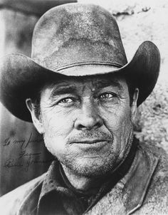 an old black and white photo of a man in a cowboy hat looking at the camera