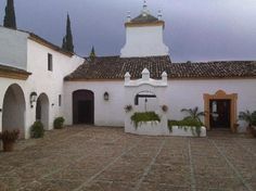 an old white building with potted plants in the courtyard