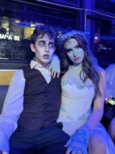 two people dressed up in costumes posing for a photo together on a bus at night