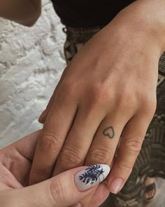 two people with tattoos on their fingers holding each other's hands and one has a leaf tattoo on it