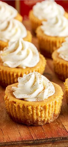 several cupcakes with white frosting on a wooden board