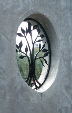 a round window with a tree design on the outside and inside, in concrete wall