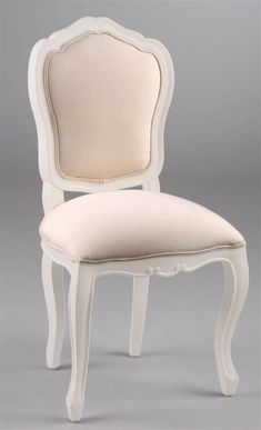 a white chair with a beige upholstered seat and back cushion on the side