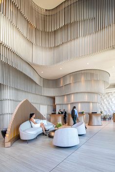 people are sitting in the lobby of an office building with wood slats on the walls