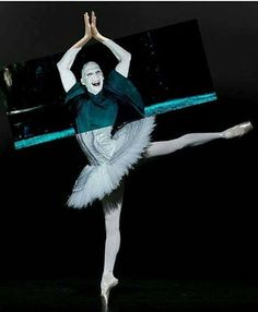 a ballerina in white and green is doing a ballet move with her arms outstretched