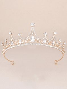 a gold tiara with crystal stones and pearls on the headband, in front of a beige background