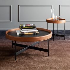 two coffee tables with books on them in a living room or dining area, one is black and the other is brown