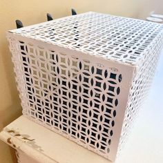 a white box sitting on top of a wooden table next to a wall with hooks in it