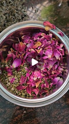 a metal bowl filled with purple flowers on top of a table