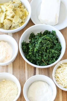 bowls filled with different types of food on top of a wooden table next to cheese