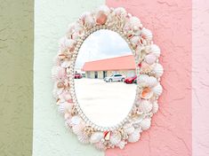 a mirror on the side of a wall with seashells hanging from it's sides