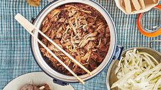 an overhead view of food on a table with chopsticks and bread in bowls