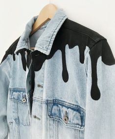 a blue jean jacket with black drips on it