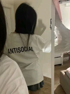 a woman standing in front of a mirror wearing an antisocial t - shirt