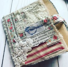 an altered piece of fabric with flowers and words on it, sitting on a white wooden surface