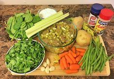 various vegetables are arranged on a cutting board with dips and seasonings in the background