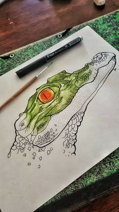 a drawing of an alligator on paper next to a pencil and marker with watercolor