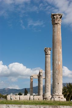 two large columns sitting next to each other on top of a lush green field under a blue sky