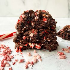 three chocolate peppermint cookies stacked on top of each other next to a candy cane