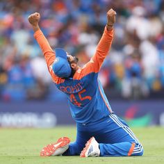 a man sitting on the ground with his arms in the air while wearing an orange and blue uniform