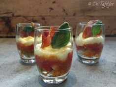 three glasses filled with food sitting on top of a table