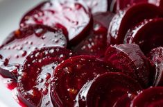 sliced beets are sitting on a white plate covered in ketchup and water