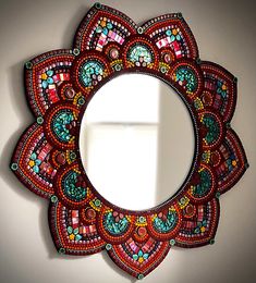 a colorful mirror hanging on the wall next to a white window with an open window sill