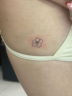 a woman's stomach with a small flower tattoo on it