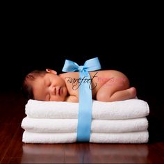 a newborn baby wrapped in white towels with a blue ribbon on it's head