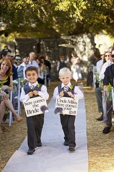 two young boys are walking down the aisle holding signs that say here comes bride and groom